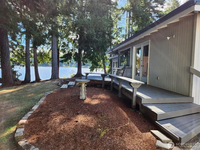 a view of a patio with table and chairs with wooden fence and large trees