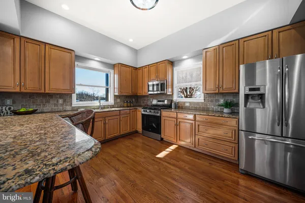 a kitchen with granite countertop wooden floors stainless steel appliances and a window
