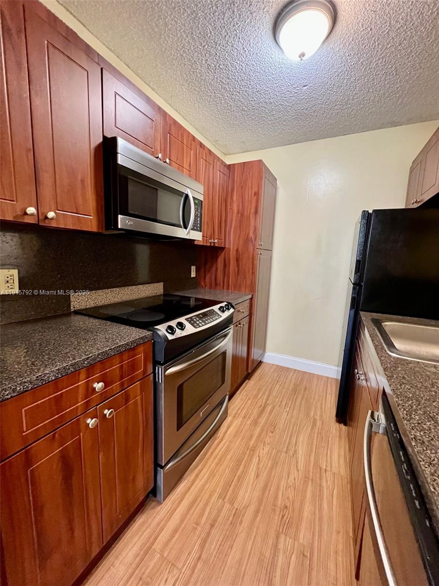 4561 West McNab Road, Unit 16 Pompano Beach, FL 33069 - Photo 3 of 14 a kitchen with stainless steel appliances granite countertop a stove a sink and a microwave
