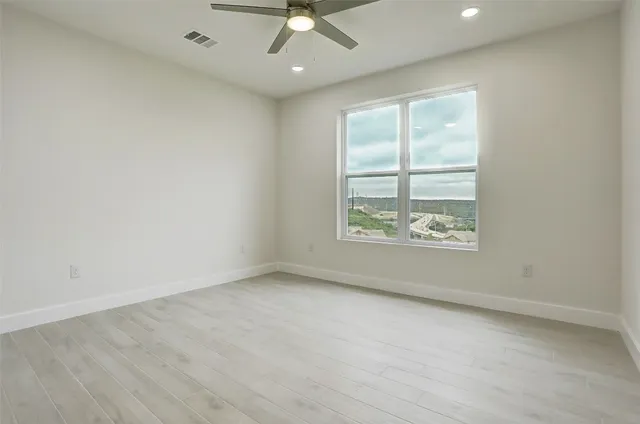 an empty room with a window and a ceiling fan