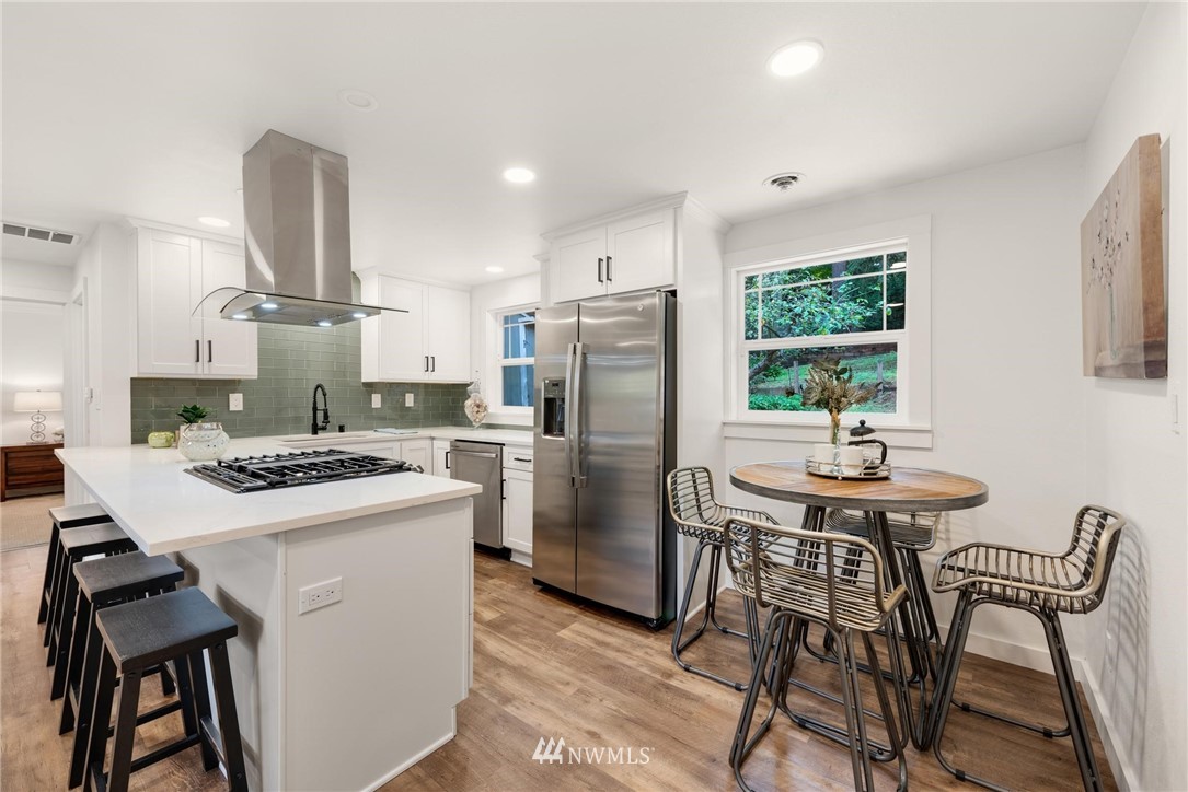 11519 32nd Avenue Northeast Seattle, WA 98125 - Photo 6 of 17 a kitchen with stainless steel appliances a table chairs and a refrigerator