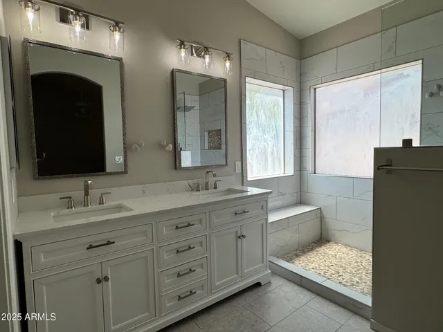 a bathroom with a double vanity sink and mirror with shower