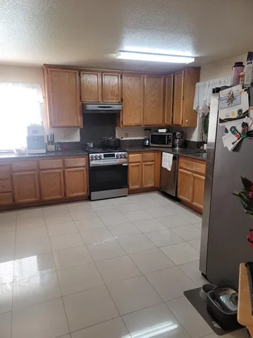 a kitchen with stainless steel appliances granite countertop a stove top oven a sink dishwasher and a refrigerator