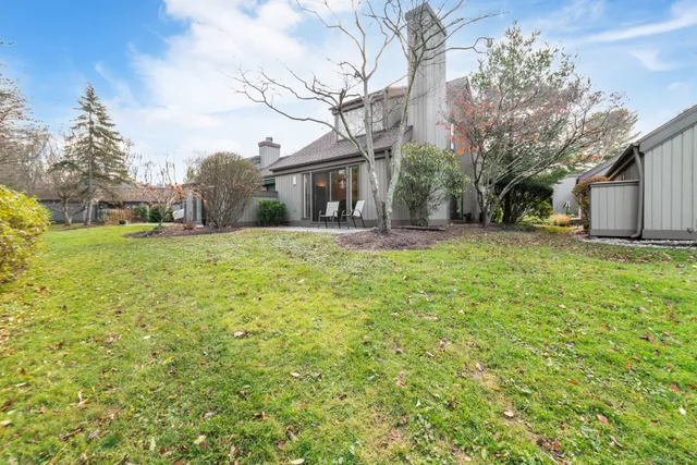 a tall house with a big yard and large trees