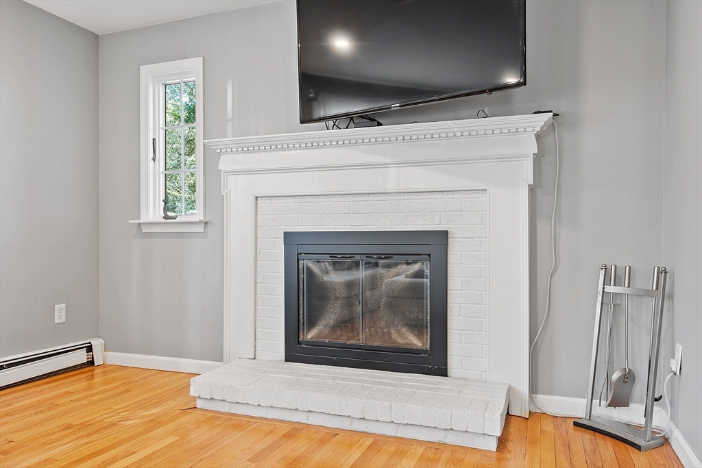 145 Virginia Road Waltham, MA 02453 - Photo 11 of 36 a view of an empty room with wooden floor and a fireplace