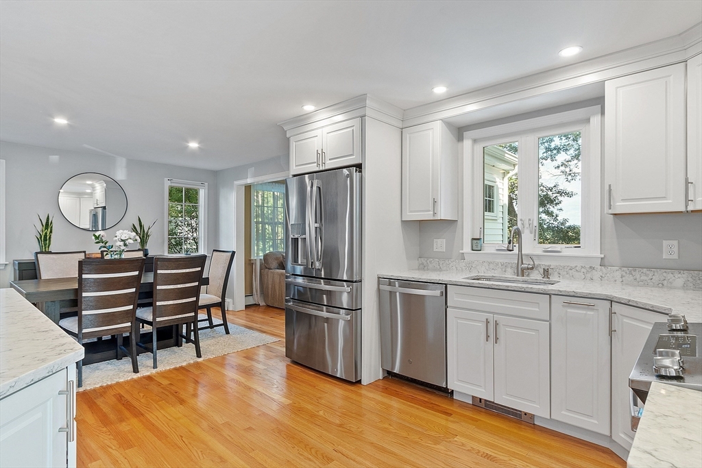 145 Virginia Road Waltham, MA 02453 - Photo 7 of 36 a kitchen with stainless steel appliances granite countertop a stove top oven a sink dishwasher a dining table and chairs with wooden floor