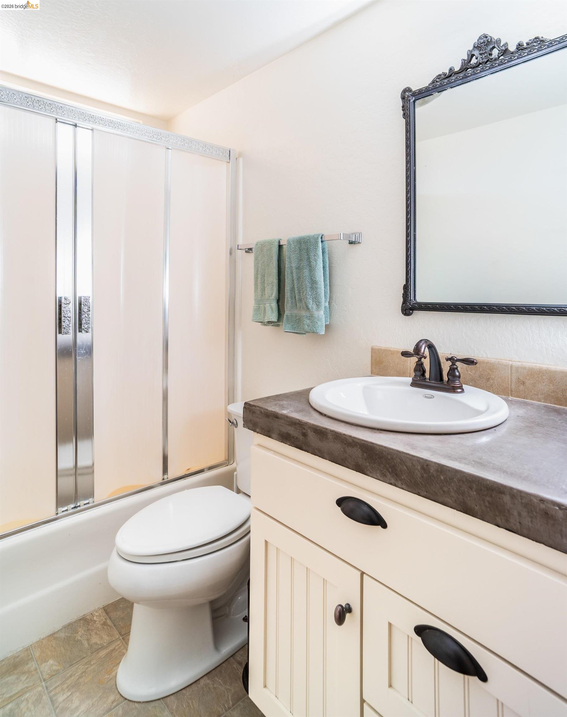 19711 Pleasantview Drive Groveland, CA 95321 - Photo 21 of 39 Bathroom featuring a white vanity with beadboard paneling, dark countertop, and an oval undermount sink with an oil-rubbed bronze faucet