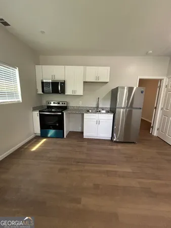 a view of kitchen with stainless steel appliances granite countertop a stove top oven a sink a dishwasher with wooden floor and cabinets