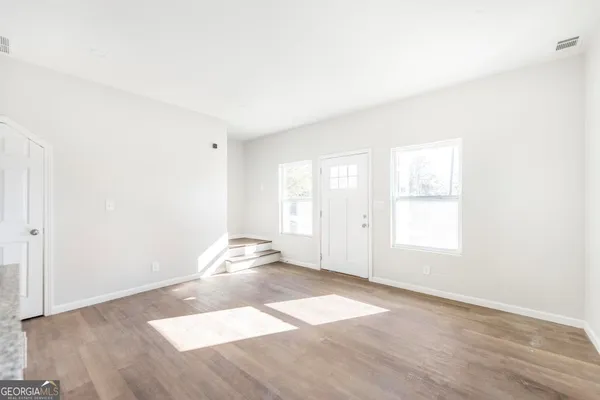 an empty room with wooden floor and windows