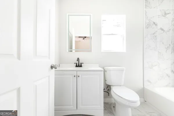 a bathroom with a toilet a sink a mirror and a window