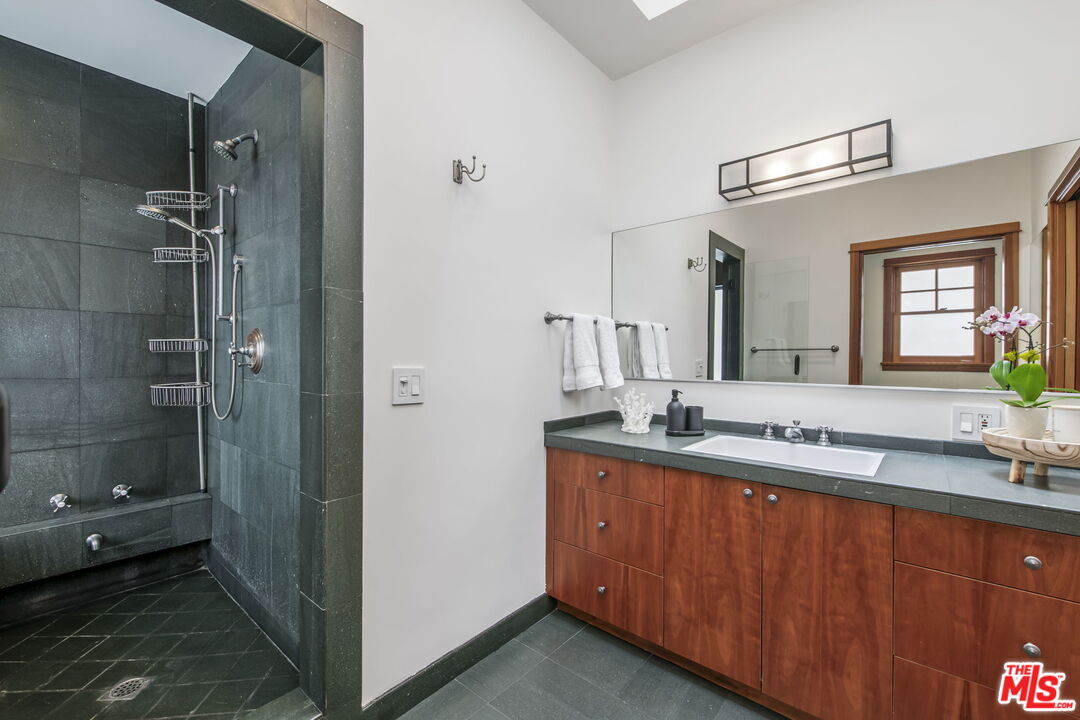 27 Latimer Road Santa Monica, CA 90402 - Photo 17 of 37 a bathroom with a granite countertop sink a large mirror and a shower