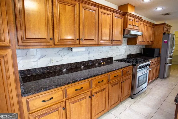 a kitchen with stainless steel appliances granite countertop a sink a stove and a granite counter top