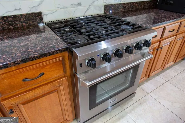 a kitchen with kitchen island granite countertop a stove top oven a sink a counter space and living room view