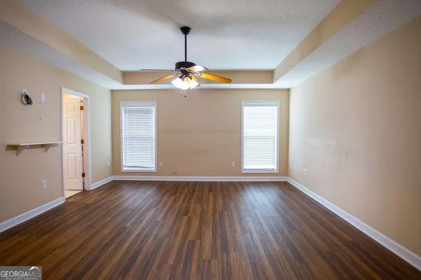a view of a livingroom with wooden floor a ceiling fan and window