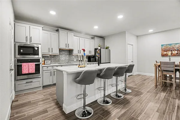 a kitchen with microwave a stove and chairs