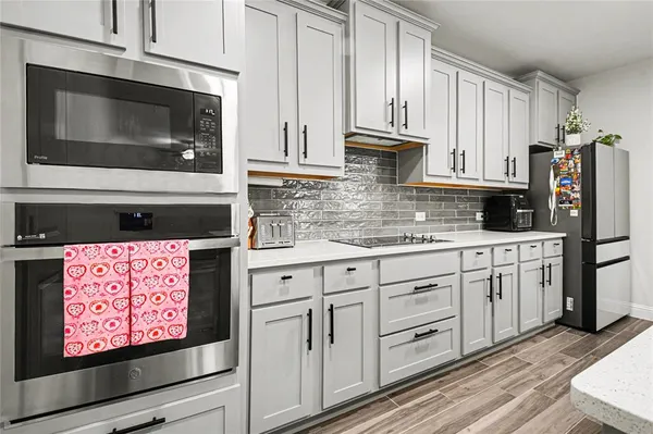a kitchen with stainless steel appliances granite countertop a refrigerator stove and white cabinets