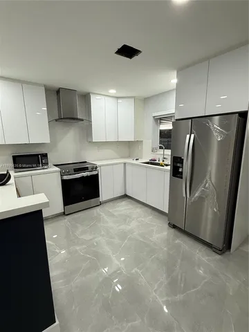 a kitchen with stainless steel appliances granite countertop a refrigerator sink and stove