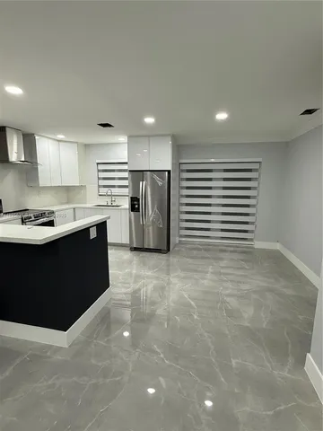 a kitchen with stainless steel appliances a sink a stove a refrigerator cabinets and a window