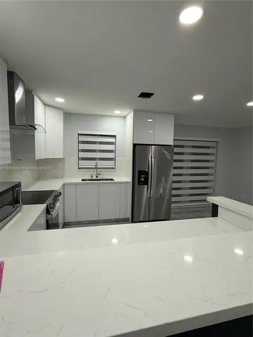 a kitchen with stainless steel appliances a refrigerator sink and microwave
