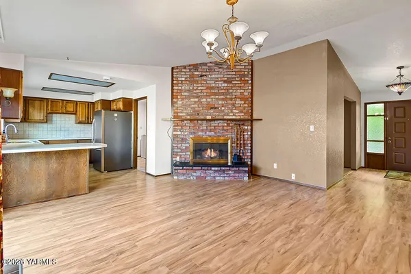a view of an empty room with wooden floor and fireplace
