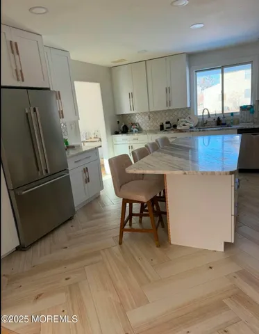 a kitchen with stainless steel appliances granite countertop a refrigerator a sink a stove a dining table and chairs