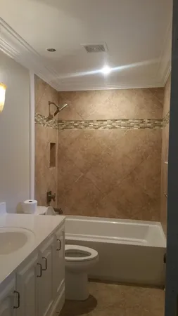 a bathroom with a granite countertop bathtub shower sink vanity and toilet