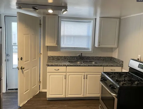 a kitchen with granite countertop a sink stove and cabinets