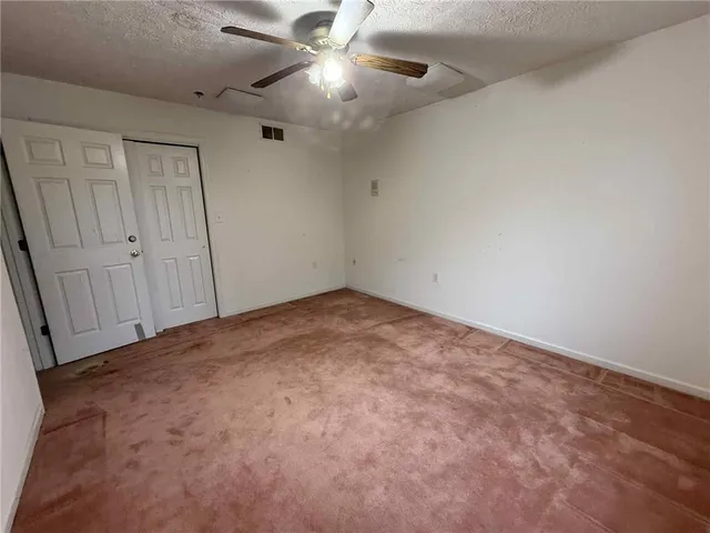 an empty room with closet and fan