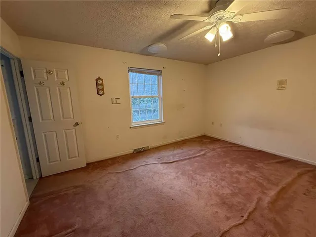 an empty room with a chandelier fan and windows