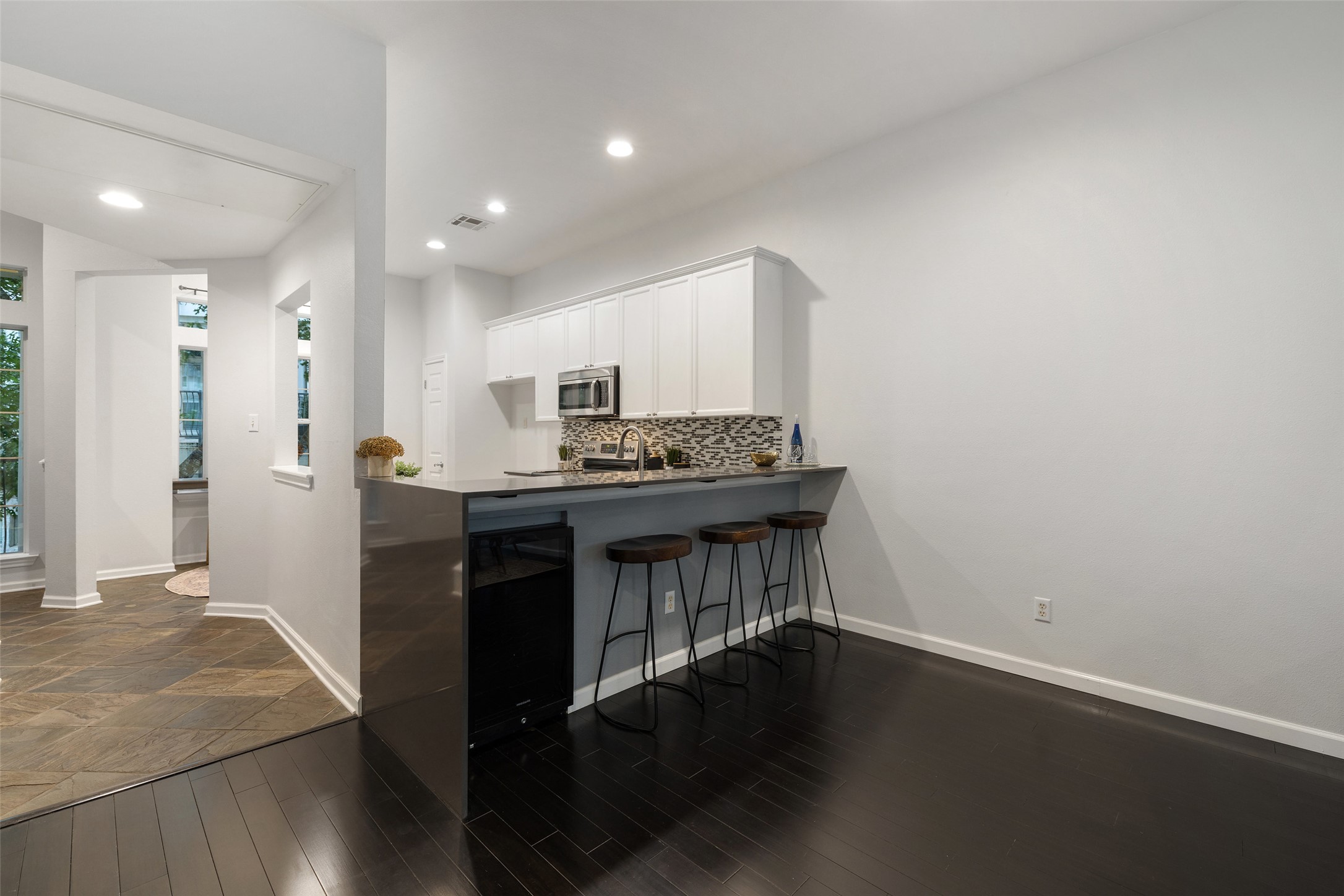 2918 Ranch To Market Road 620, Unit O282 Austin, TX 78734 - Photo 11 of 40 Kitchen with a kitchen breakfast bar, stainless steel microwave, tasteful backsplash, visible vents, and white cabinetry