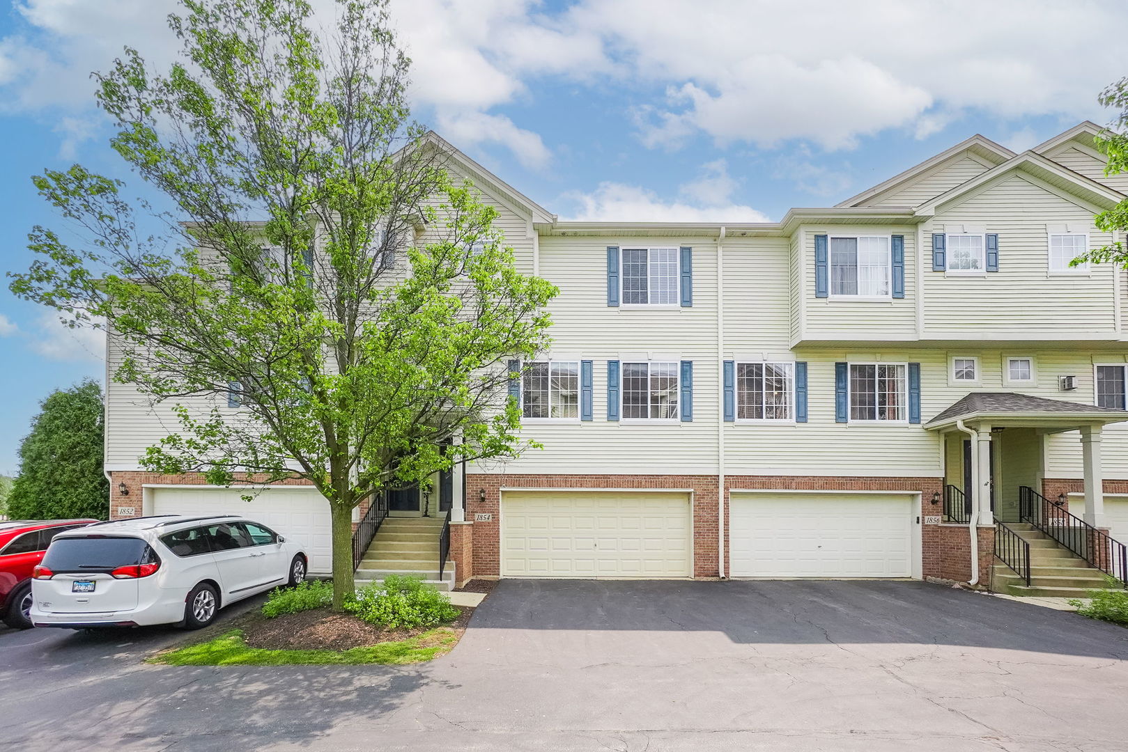 a front view of a house with a garden and trees