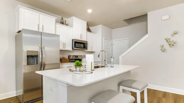 a kitchen with stainless steel appliances a sink a microwave a refrigerator and white cabinets