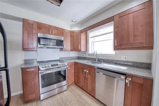 a kitchen with stainless steel appliances granite countertop a sink stove microwave and window