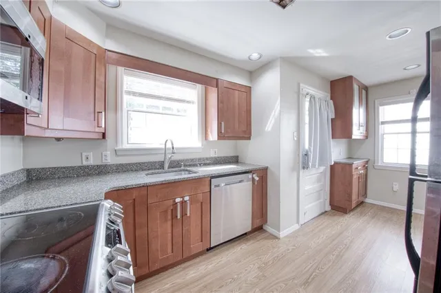 a kitchen with granite countertop a sink cabinets stainless steel appliances and window