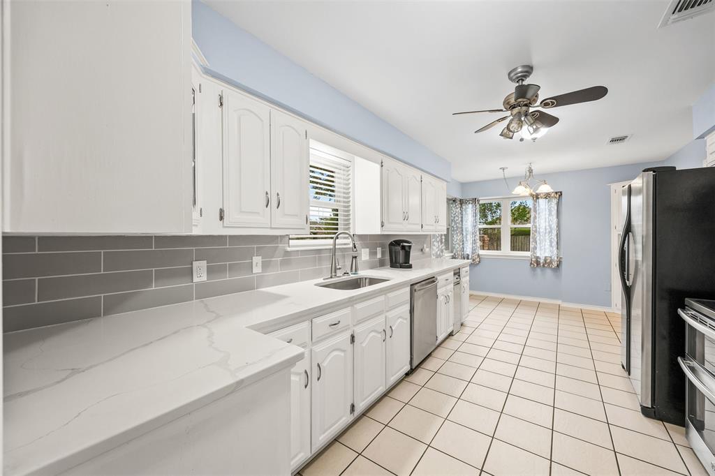 909 Valley View Avenue Red Oak, TX 75154 - Photo 11 of 37 a large kitchen with a stove a sink dishwasher a refrigerator and white cabinets with wooden floor