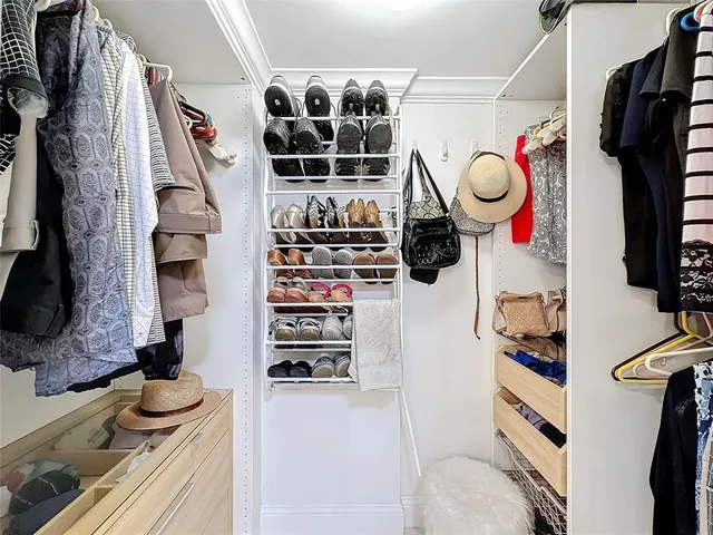a view of walk in closet with clothes and shoes