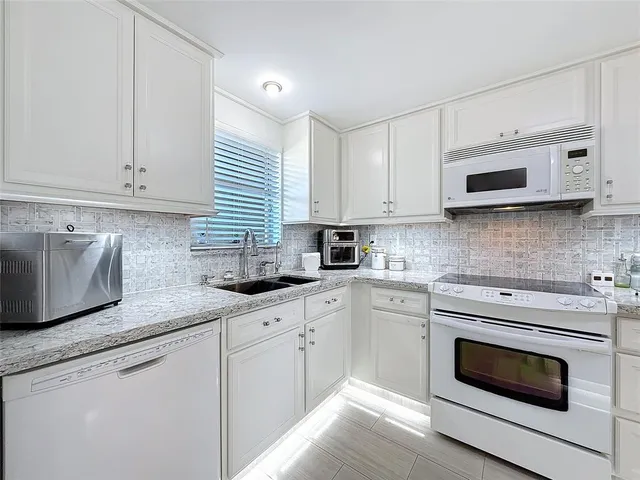 a kitchen with granite countertop white cabinets and white appliances