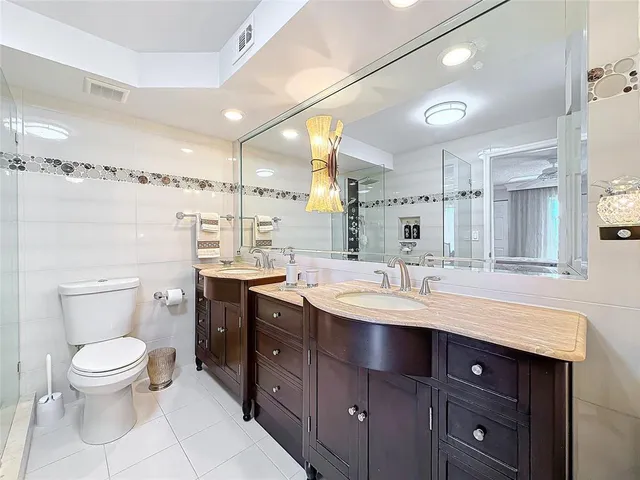 a bathroom with a toilet a double vanity sink and a mirror