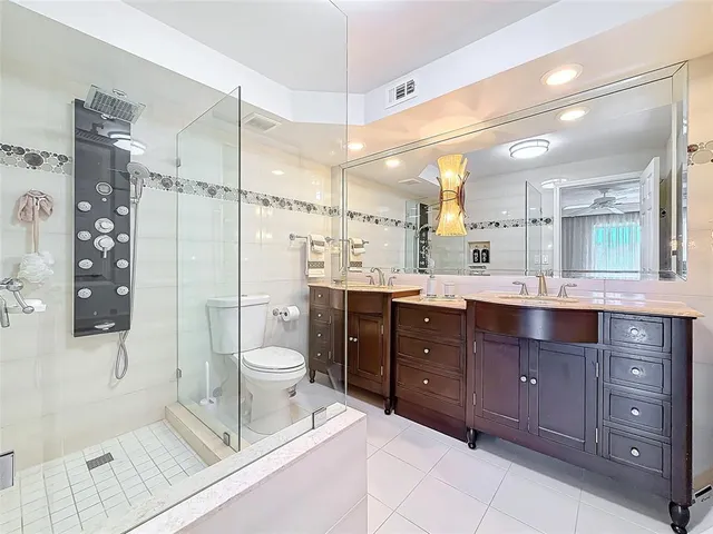 a spacious bathroom with a double vanity sink toilet mirror and shower