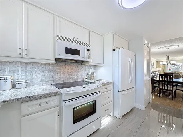 a kitchen with stainless steel appliances white cabinets white stove a sink and a refrigerator