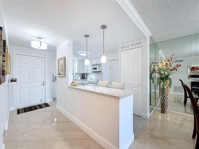 a room with kitchen island a chandelier and entryway