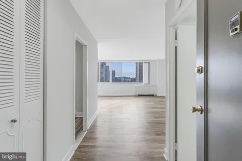 a view of a hallway with wooden floor and a bathroom