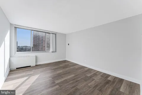 a view of an empty room with wooden floor and a window