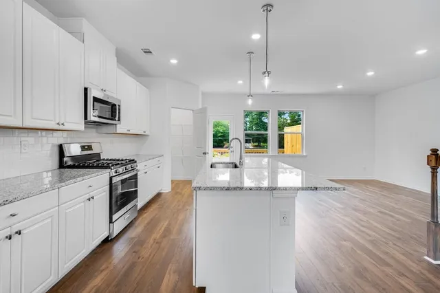 a view of an empty room with wooden floor and a ceiling fan