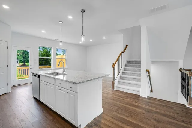 a view of a livingroom with wooden floor a ceiling fan and kitchen space