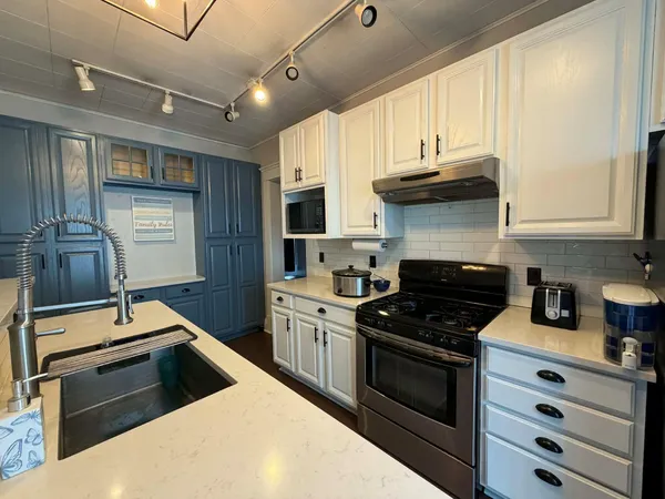 a kitchen with kitchen island granite countertop a sink appliances cabinets and a counter top space