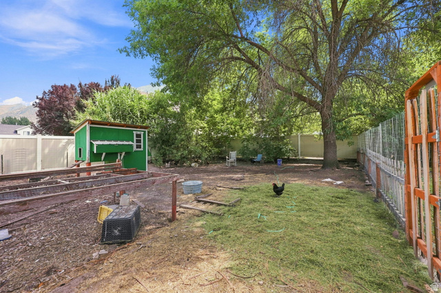 154 West 400 North Springville, UT 84663 - Photo 32 of 43 Expansive yard featuring a mature shade tree, a vibrant green chicken coop, a partial privacy fence, and raised garden beds