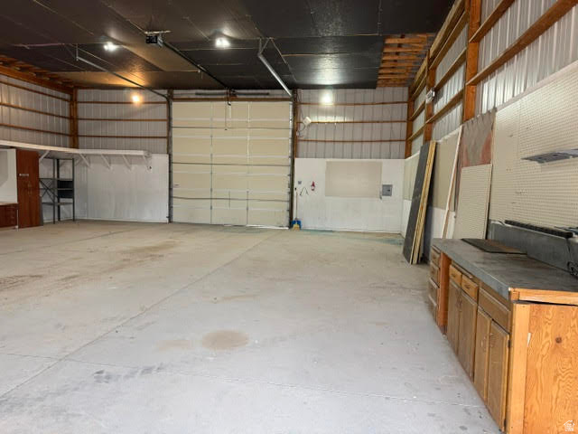 1124 Washam Road Green River, WY 82938 - Photo 13 of 35 Spacious interior featuring a large garage door, concrete flooring, exposed wood beam ceiling, metal wall panels, and built-in wood cabinetry with a countertop