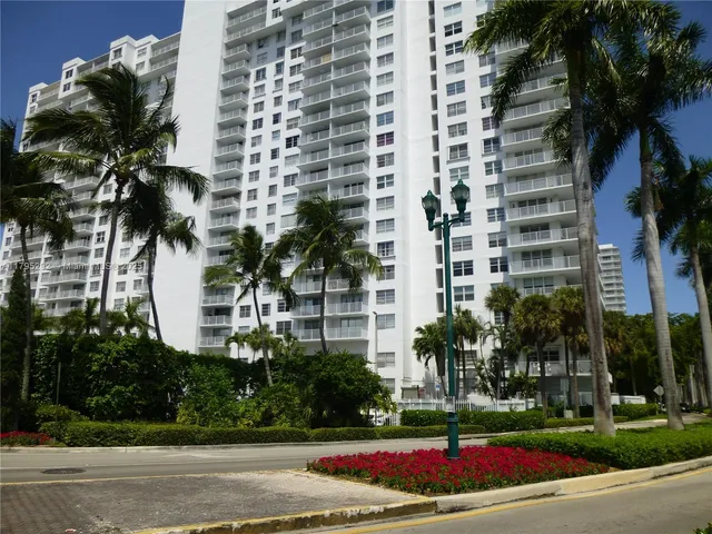 a view of a white building among the street view and palm trees
