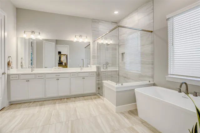 a bathroom with a tub a sink a mirror and a shower